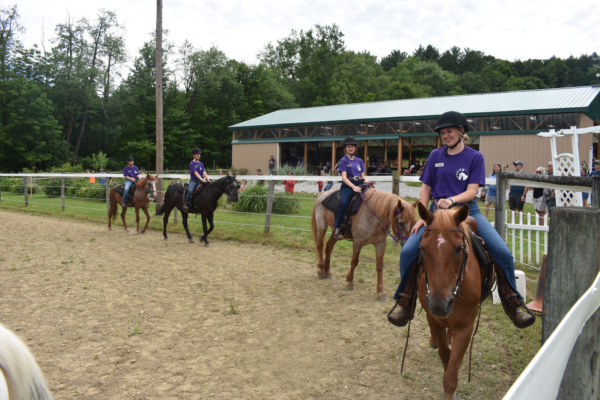 A group of people are riding horses in a fenced in area.