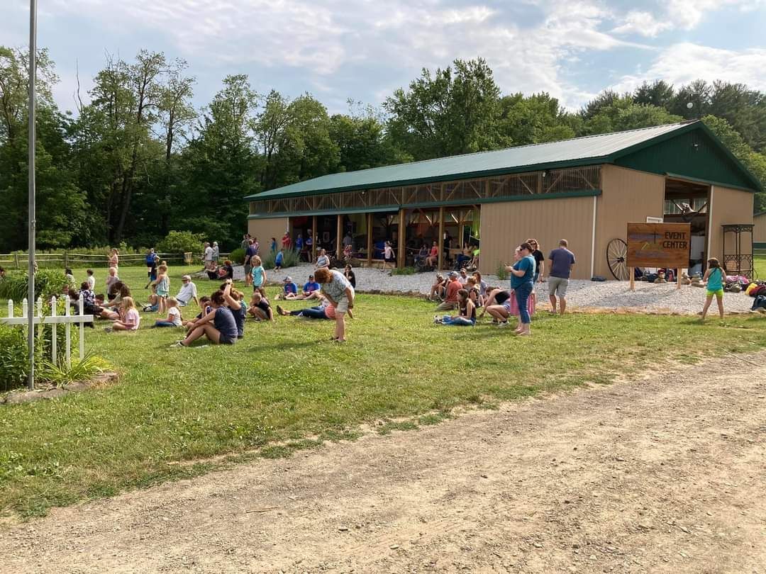 A group of people are sitting in a grassy field in front of a building.