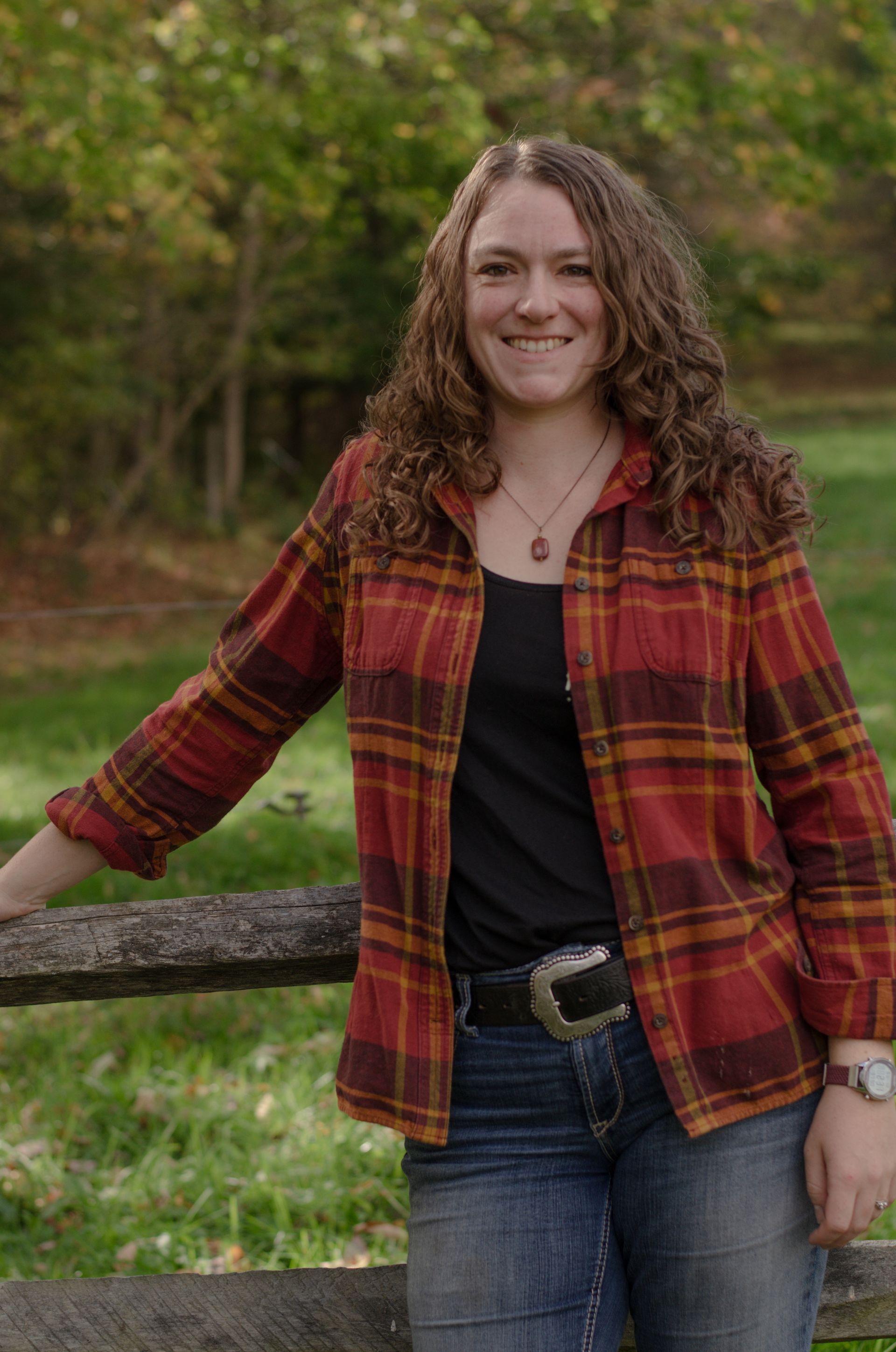 A woman wearing a scarf and a sweater is standing in front of a house.
