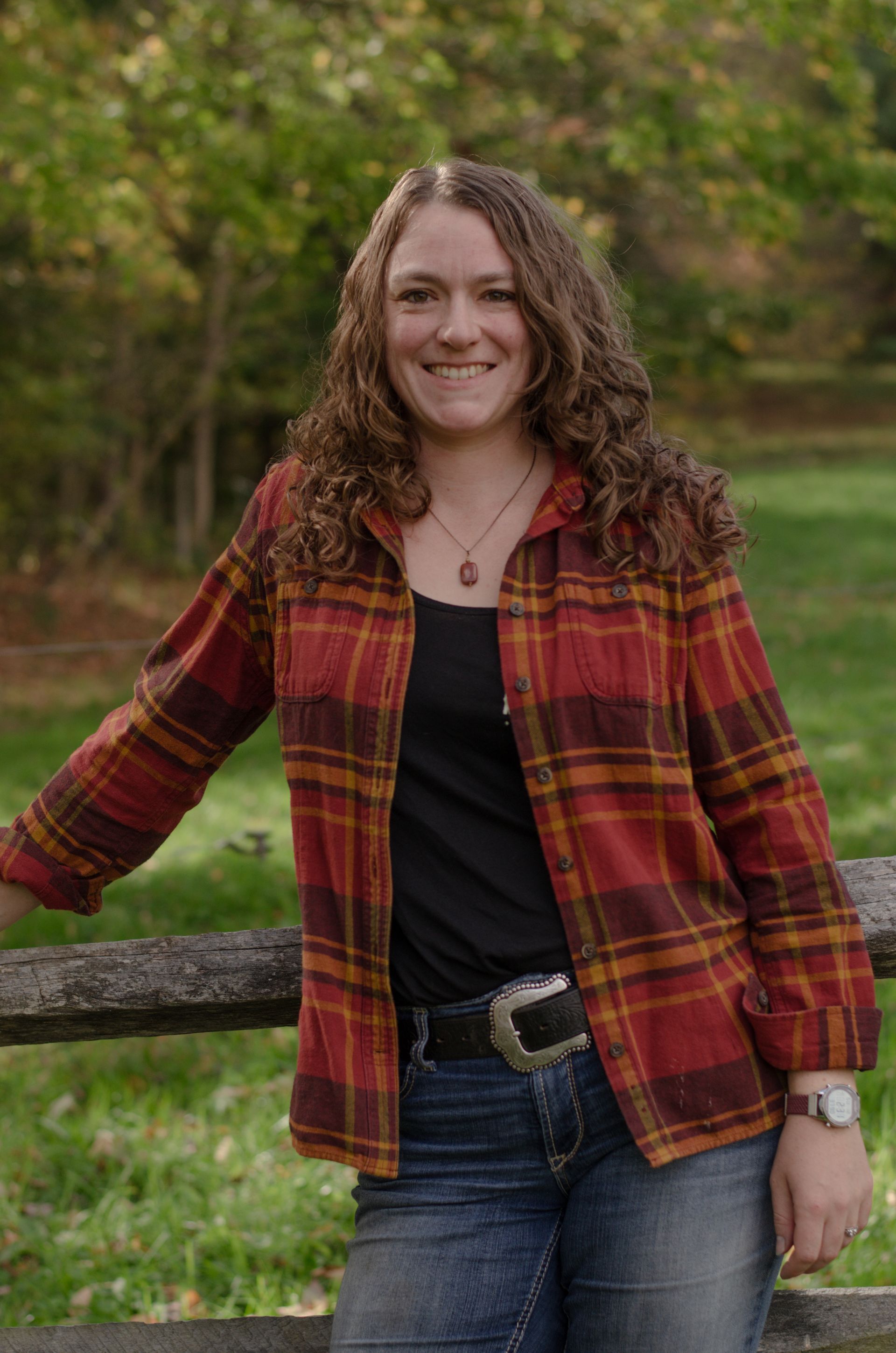 A woman wearing a scarf and a sweater is standing in front of a house.