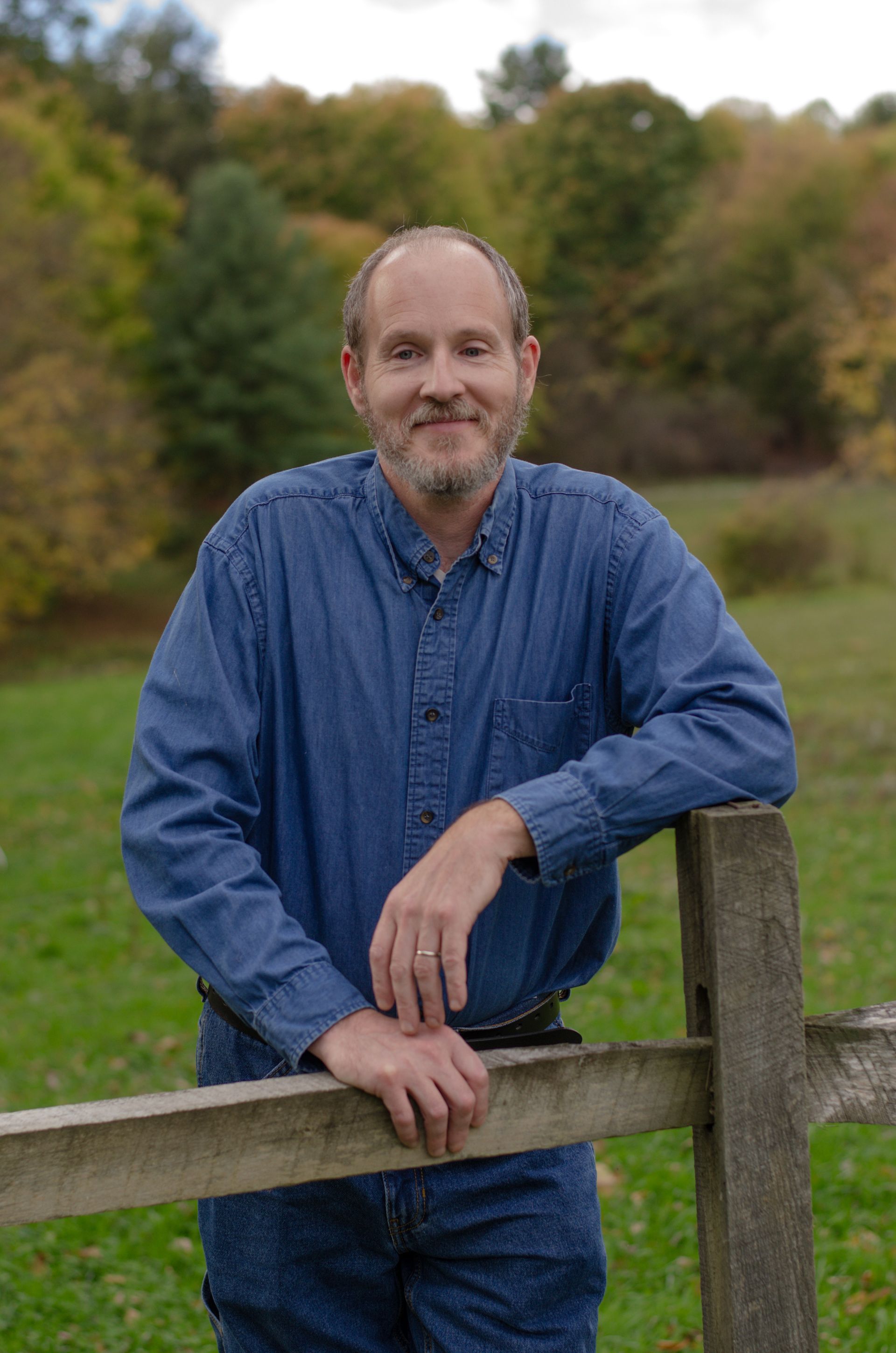 A man with a beard wearing an orange shirt and a hat