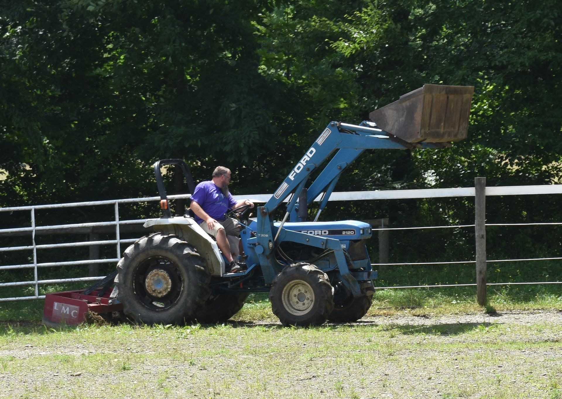 A man is driving a blue ford tractor