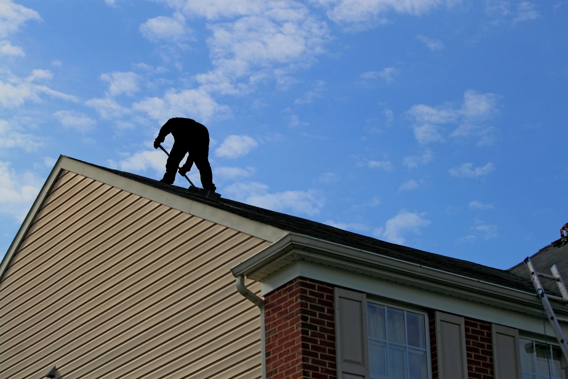 Roofers on a roof removing shingles. 