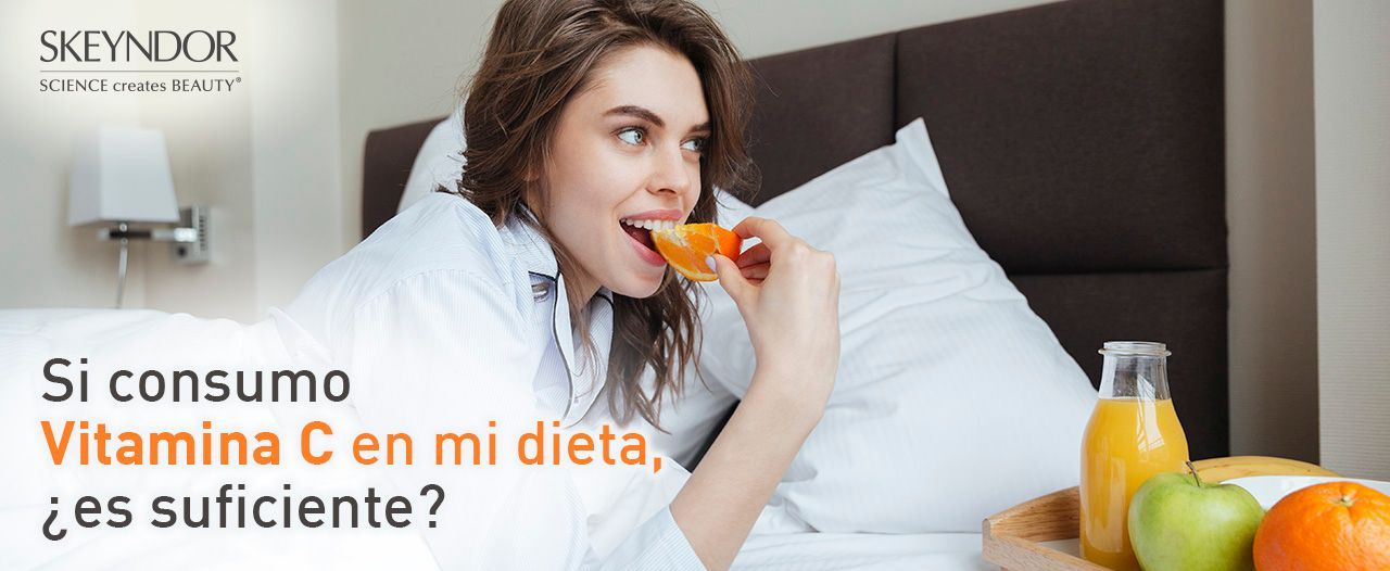 Una mujer está sentada en la cama comiendo una manzana y bebiendo jugo de naranja.