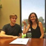 A man and a woman are sitting at a table in front of a window.