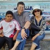 A man , woman and child are sitting on a bench in front of a sign.