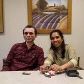 A man and a woman are sitting at a table in front of a painting.
