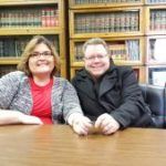 A man and a woman are sitting at a table in a library.