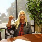 A woman is sitting at a desk holding a key.