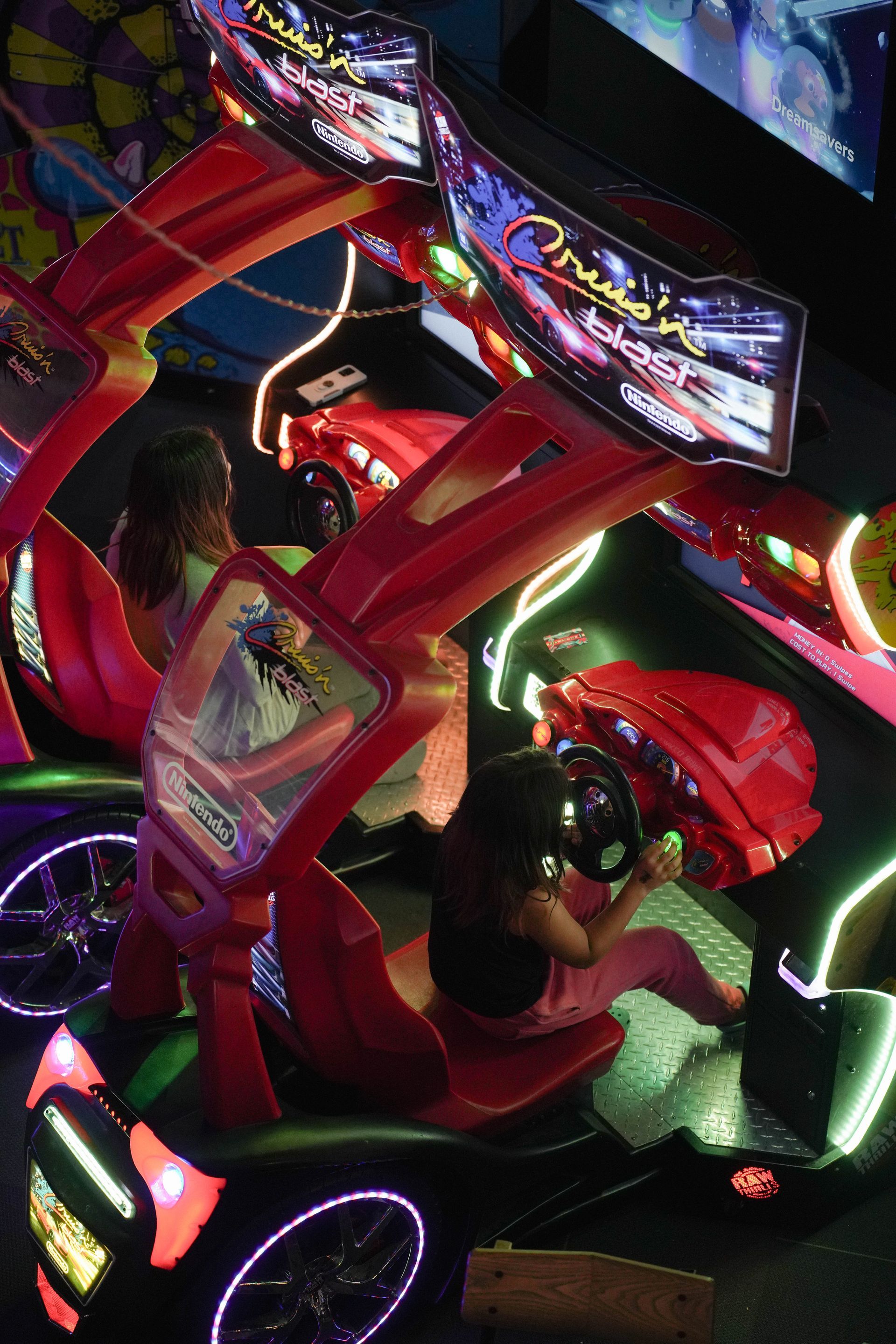 Skee-Ball arcade game with five lanes, illuminated ramps, and digital scoreboards, a carnival setting.