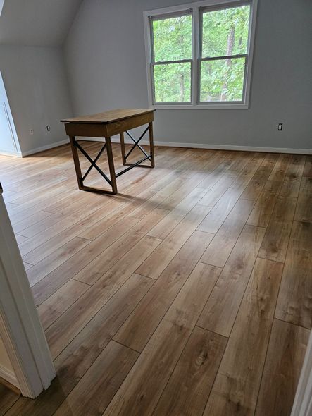 Wooden table in a room with hardwood floors and a window with a view of trees.