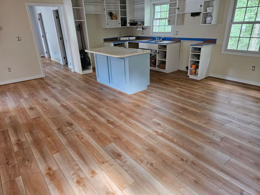 Kitchen with light wood-look flooring and light blue island. Cabinets are white and under construction.