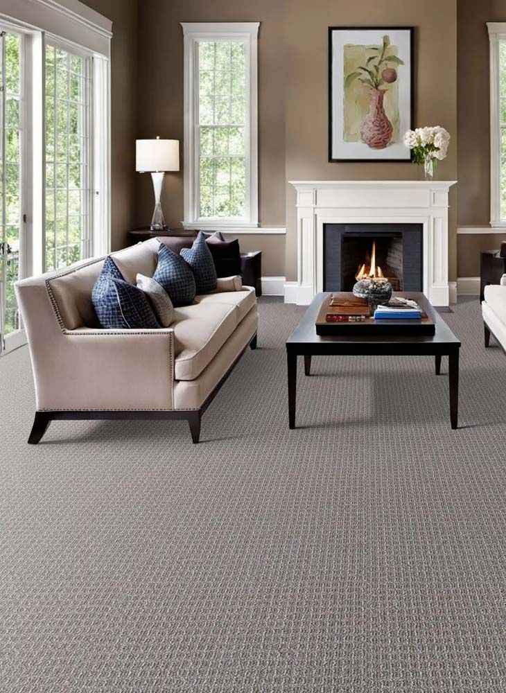 Living room with beige sofa, fireplace, and gray patterned carpet.