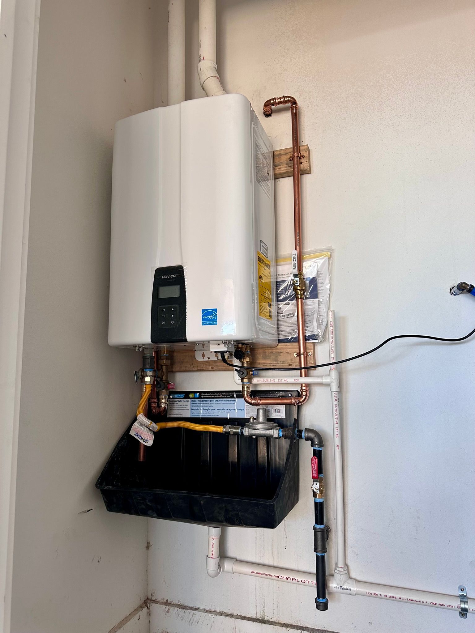 Square shower drain with concentric black rings on a white tile background.