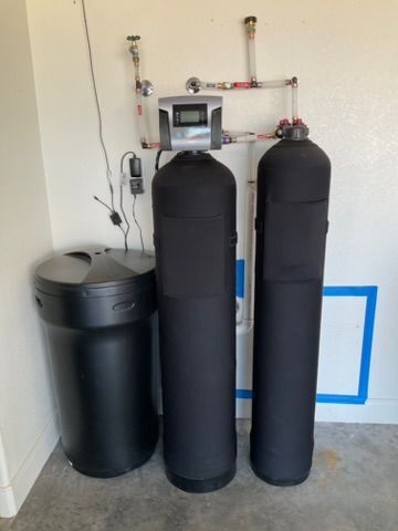 Shiny chrome faucet with glass soap dispensers in a bathroom.
