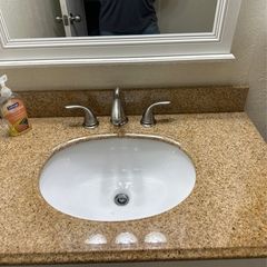 Bathroom sink with a white oval basin, granite countertop, and brushed nickel faucet.
