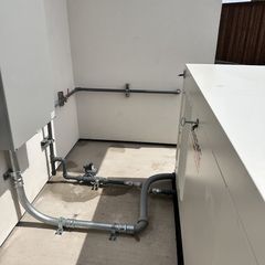 Electrical conduits and components on a white wall, with a large white box structure.