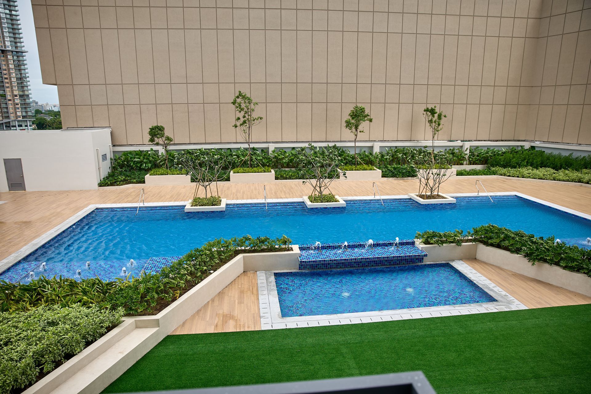 Luxurious outdoor pool area and garden deck at Connor Serviced Residences Quezon City, featuring multiple swimming pools and landscaping