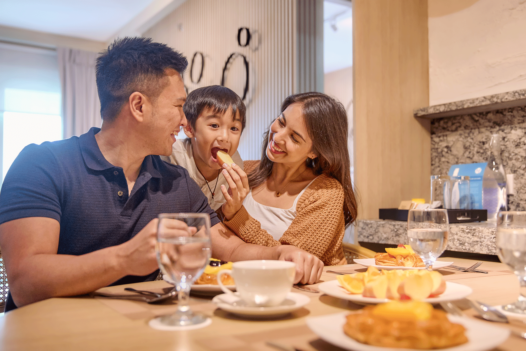 Family enjoying breakfast at Connor Serviced Residences, a premier hotel near Greenhills Manila, with parents feeding their excited child