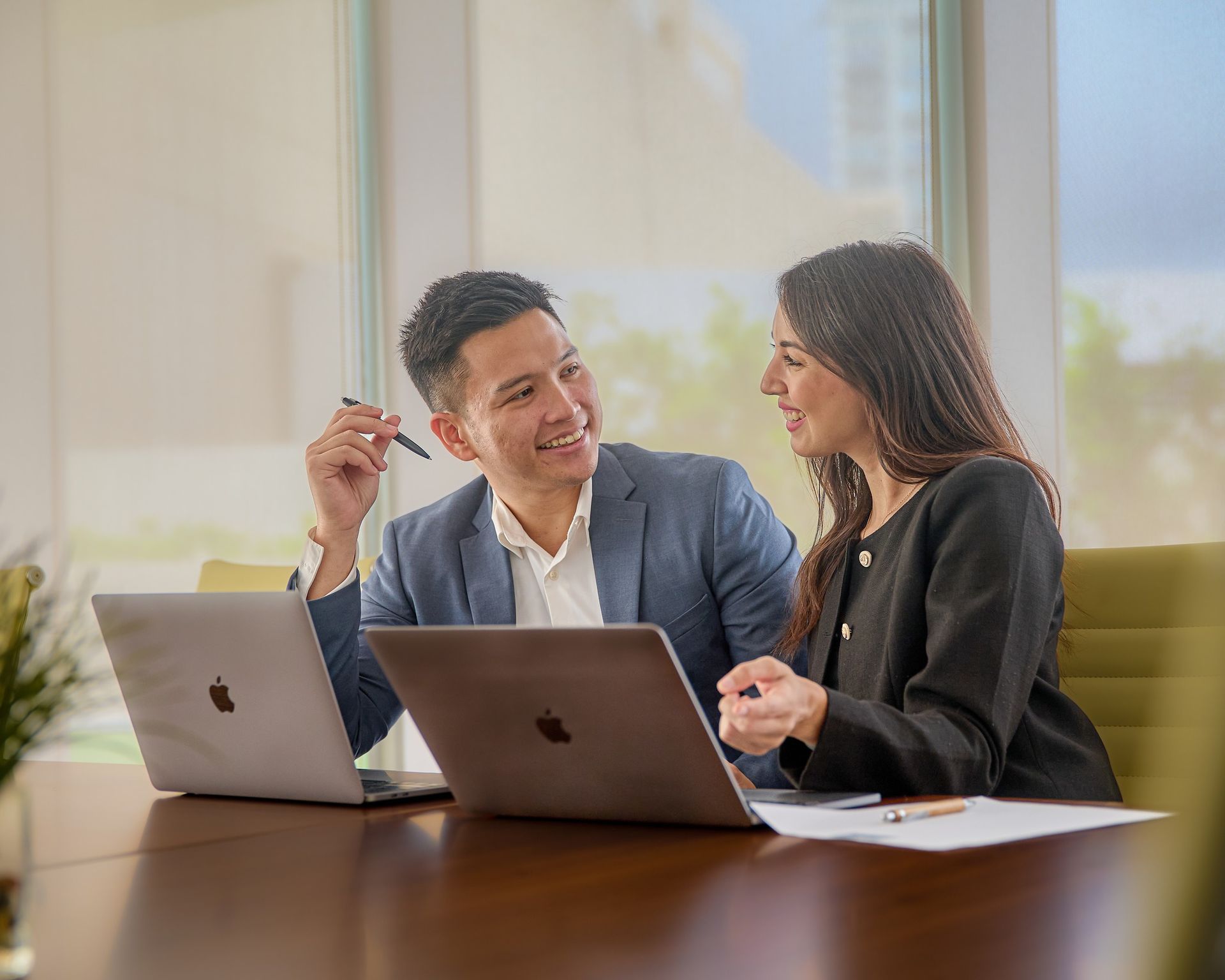 A man and a woman are sitting at a table with laptops.