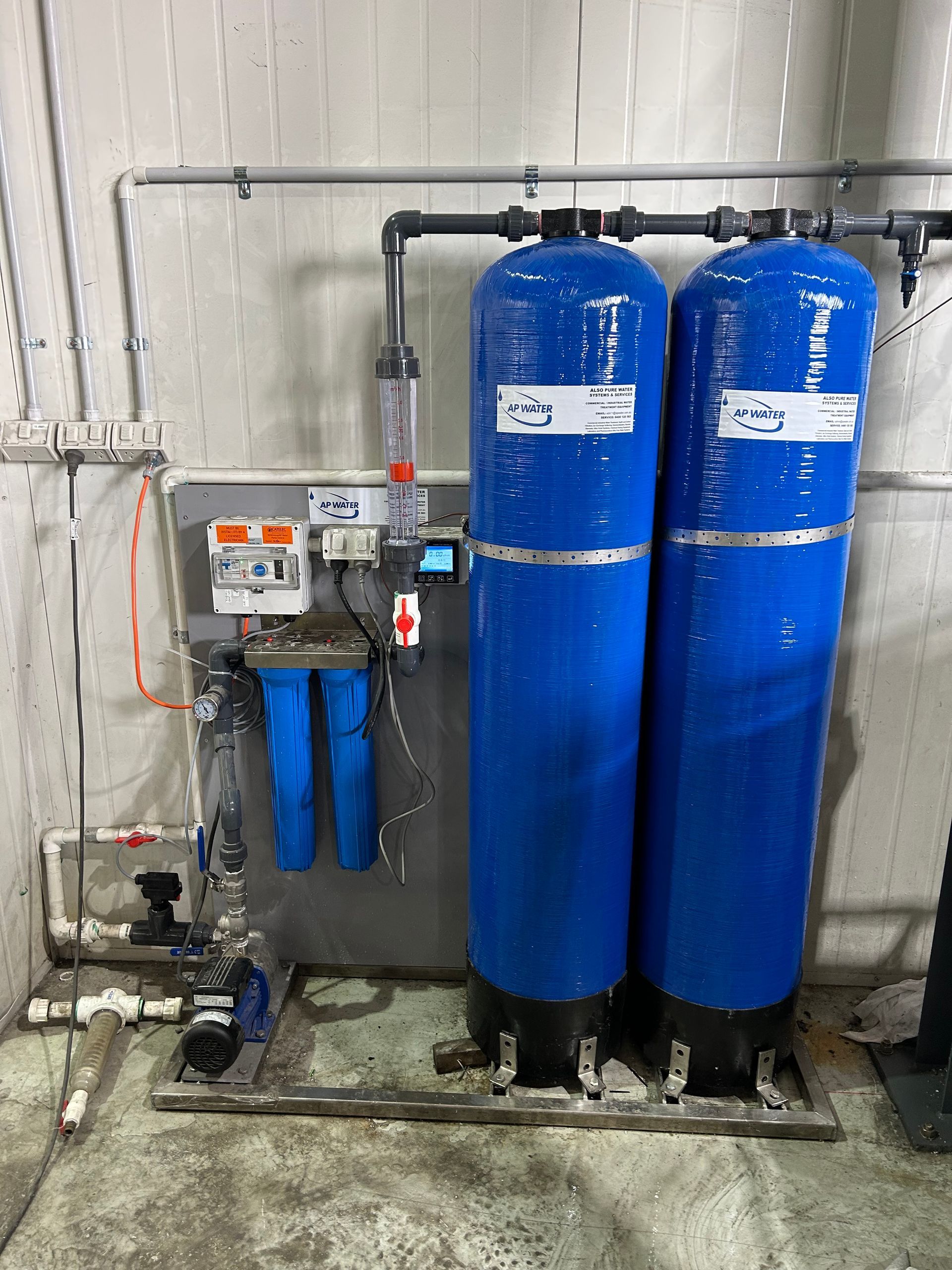 Commercial water purification system featuring twin blue deionisation tanks and pre-filters, used in industrial settings for high-purity water production.