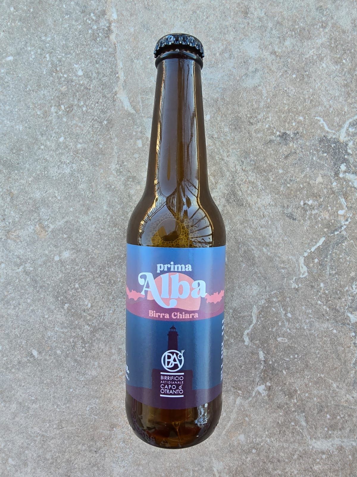 Une bouteille de bière prima alba est posée sur une surface en pierre.