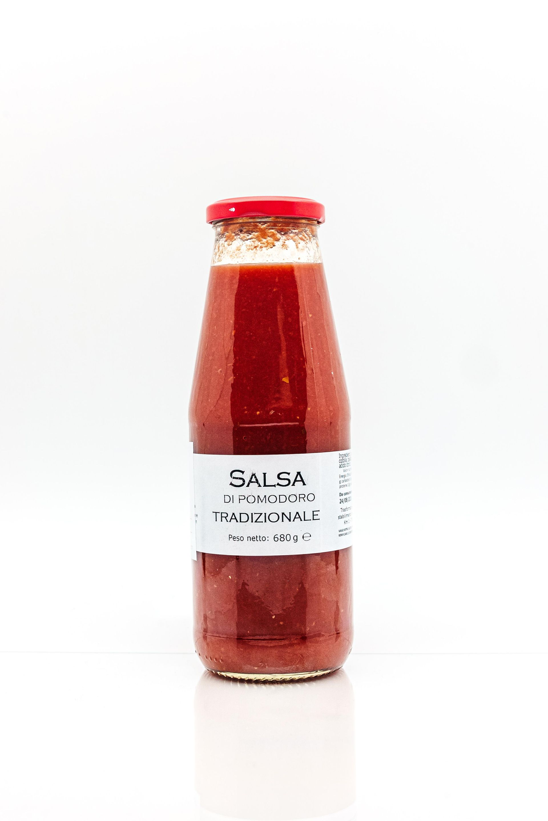 Une bouteille de sauce tomate est posée sur une surface blanche.