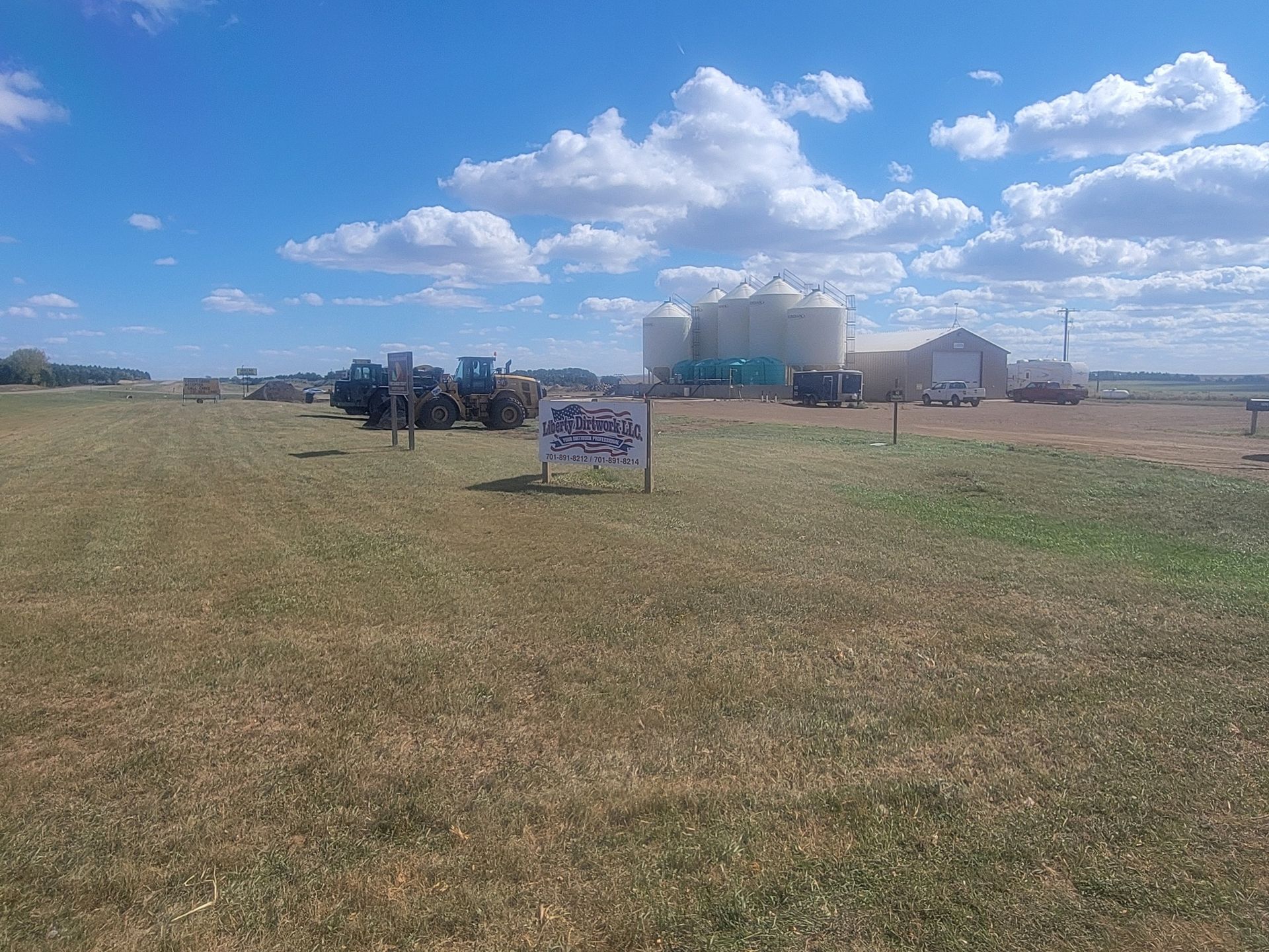 A large grassy field with a sign in the middle of it