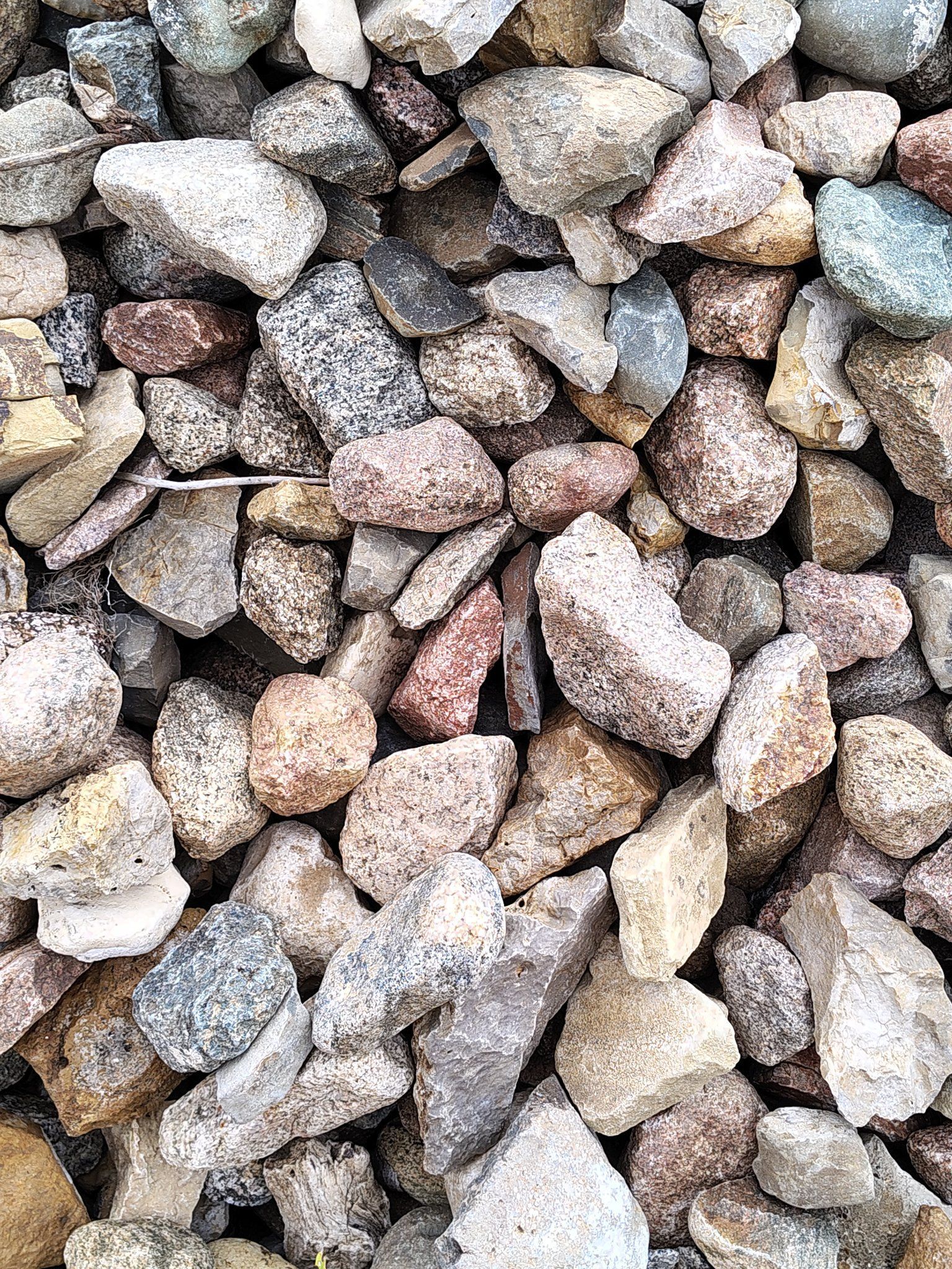 Close-up of a pile of gravel with varied colors like beige, brown, gray, and speckled tones.