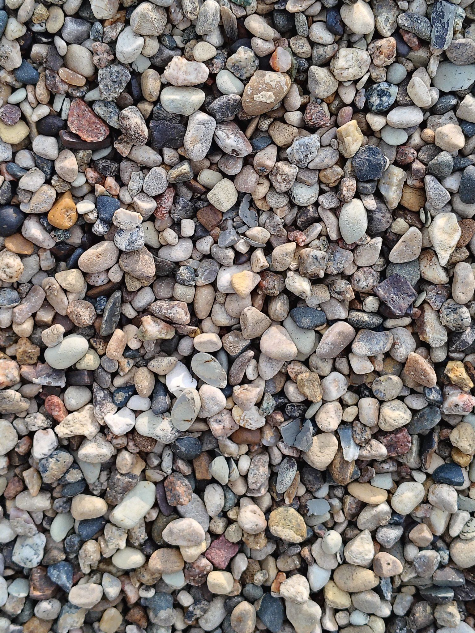 Gravel, small rounded stones, varying colors including beige, gray, black, and brown.