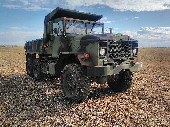 Camouflaged military truck in a field.