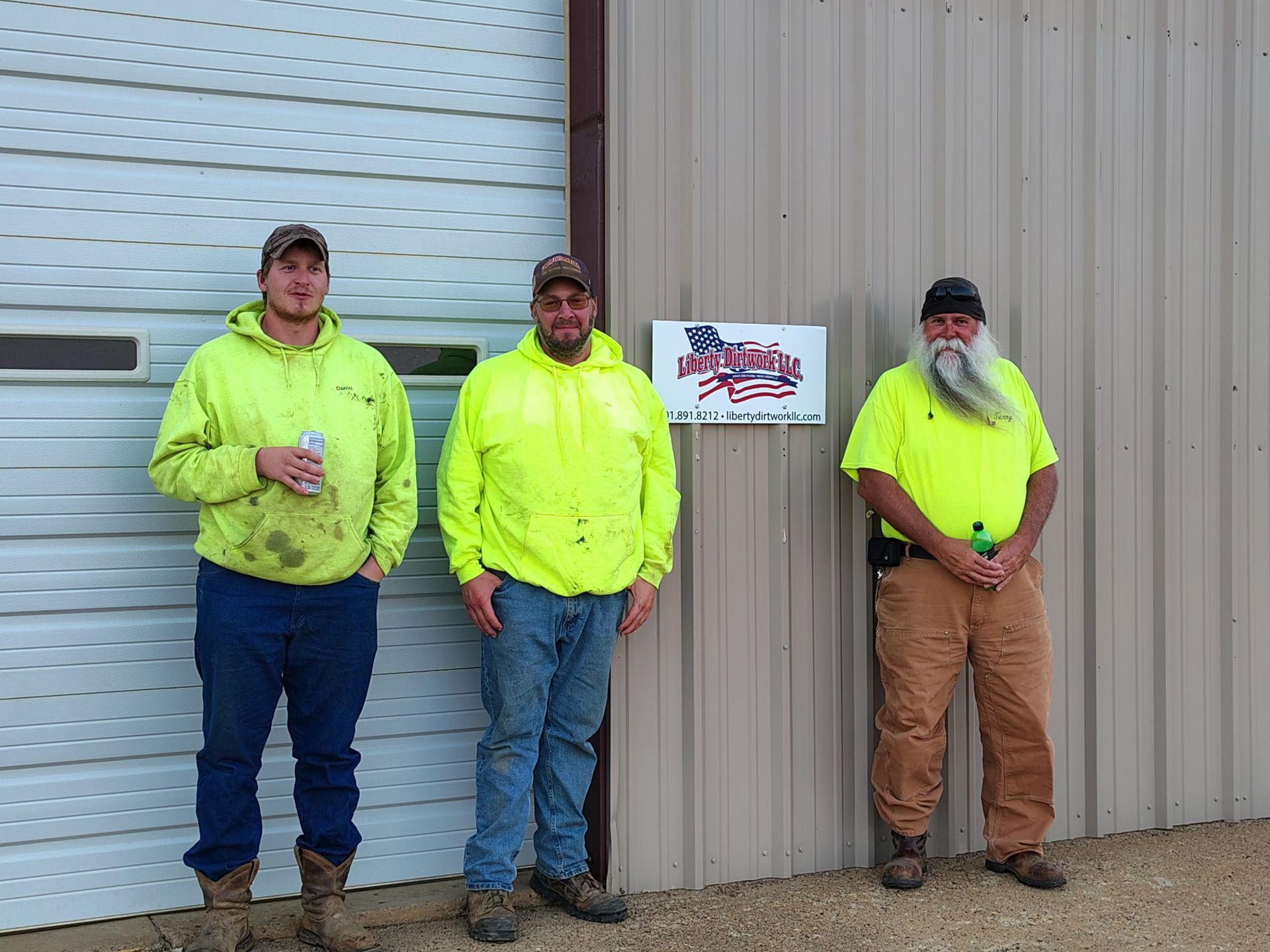 Four people in safety vests working near a truck on a gravel lot.