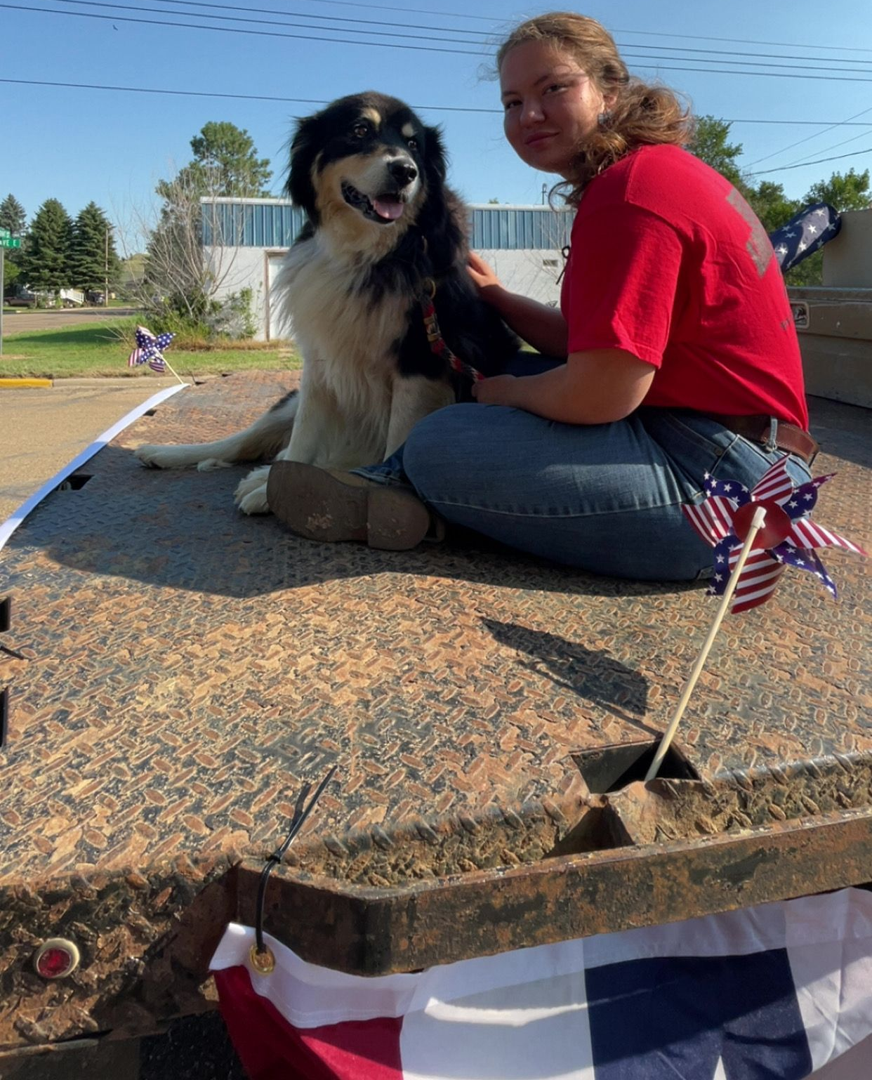 A black and white dog wearing a red shirt that says duck tour