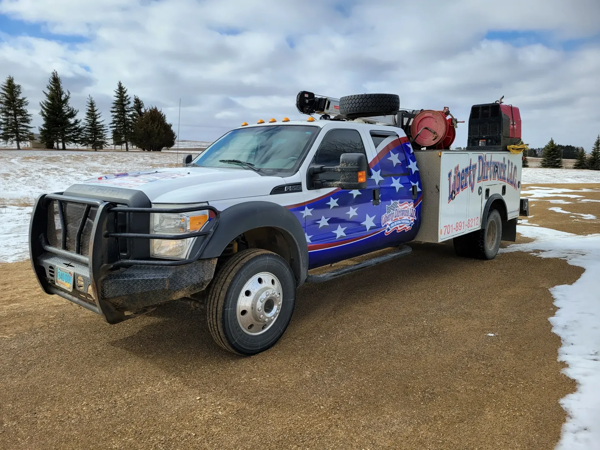 A white truck with an american flag wrap is parked in a snowy field.