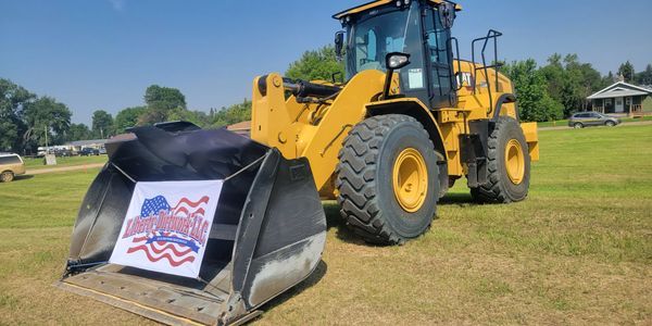 A large yellow bulldozer is parked in a grassy field.