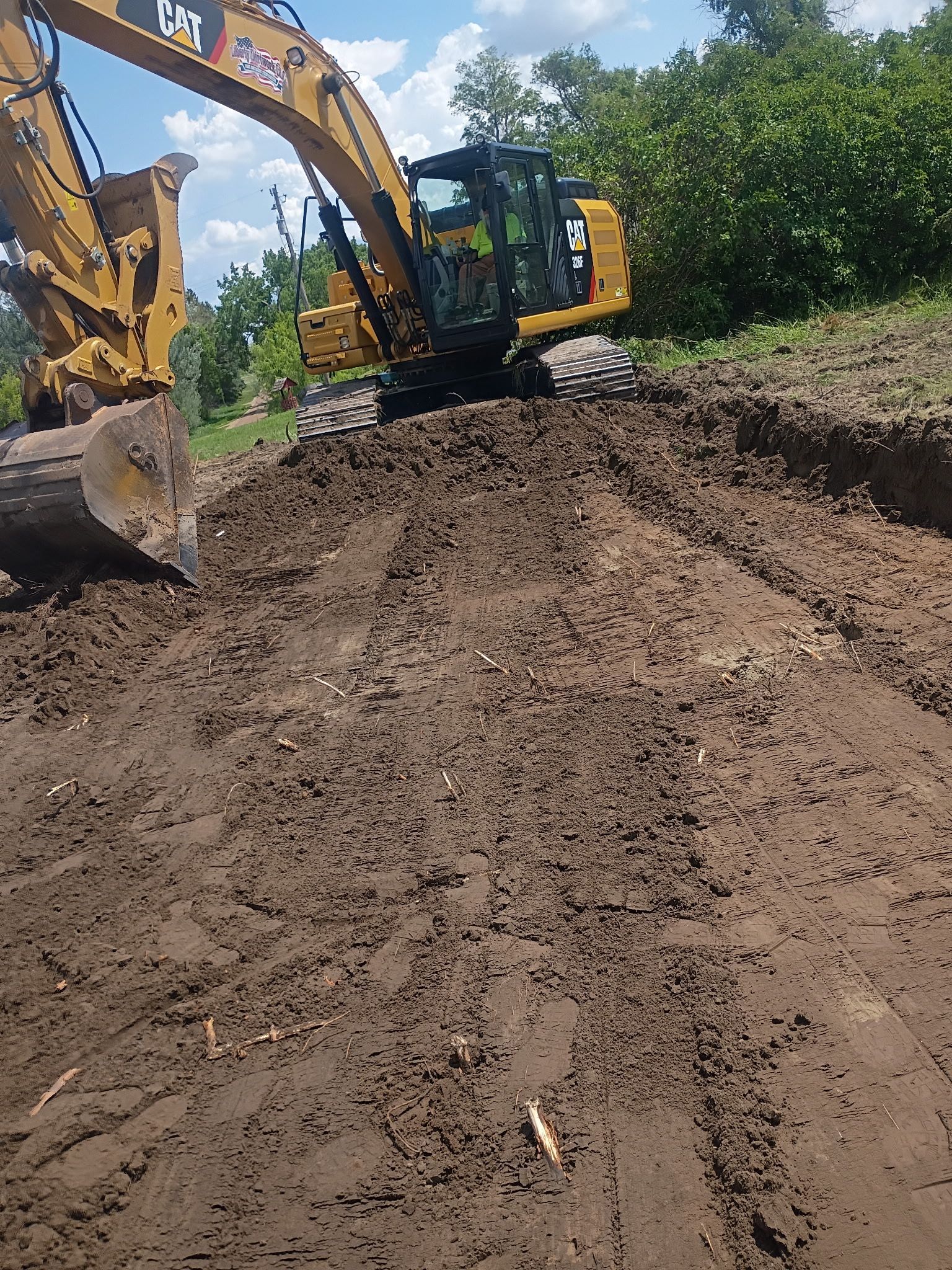 Yellow excavator digging in brown earth, sunny day.