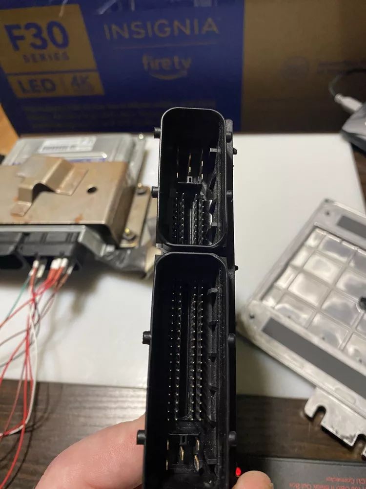 A person is holding a piece of electronic equipment in front of a box that says insignia