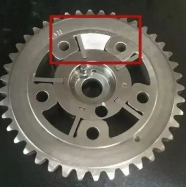 A close up of a metal gear on a black surface