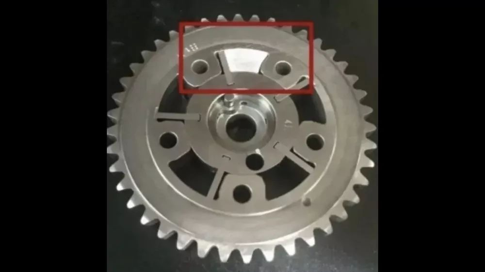 A close up of a metal gear on a black surface.