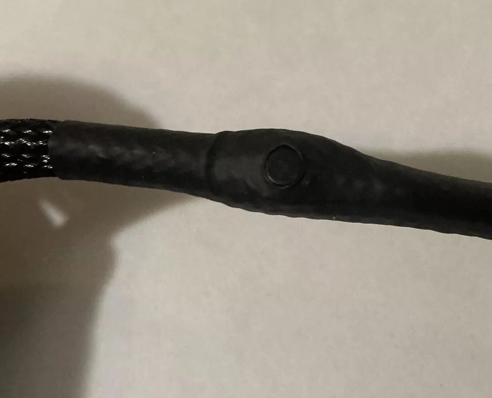 A close up of a black cable with a button on the end