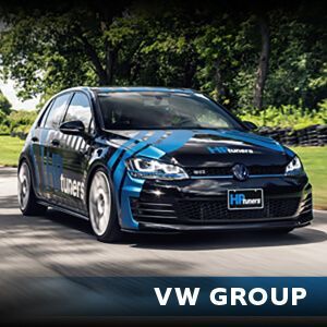 A blue and black volkswagen golf is driving down a road.