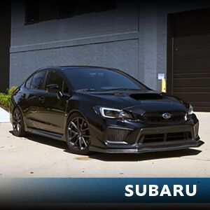A black subaru is parked in front of a building
