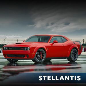 A red dodge challenger is parked on a wet track.