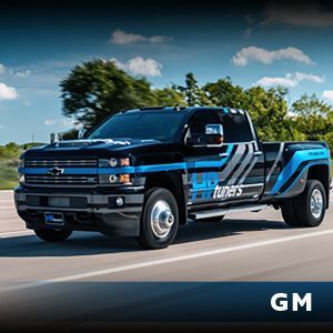 A black and blue truck is driving down a road.