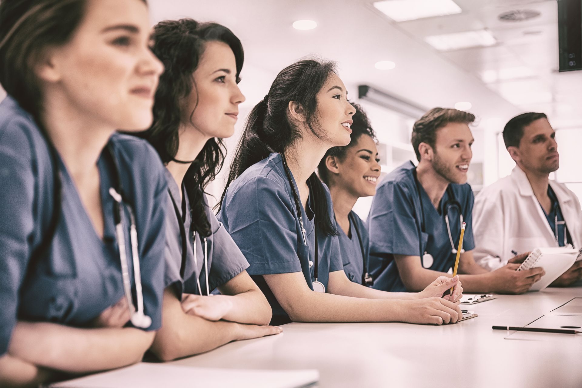 A group of doctors and nurses are sitting at a table.