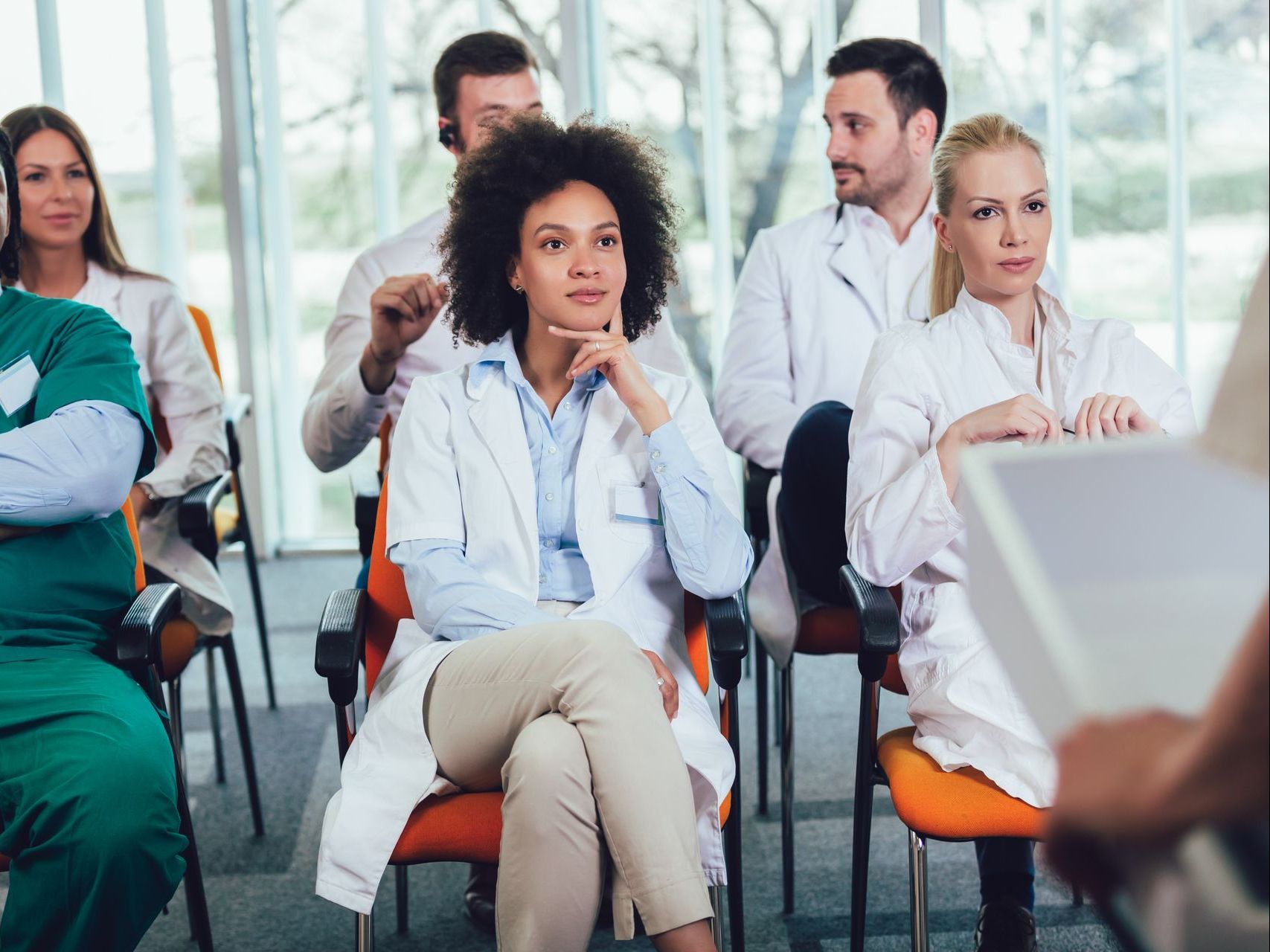 A group of doctors are sitting in chairs listening to a presentation.