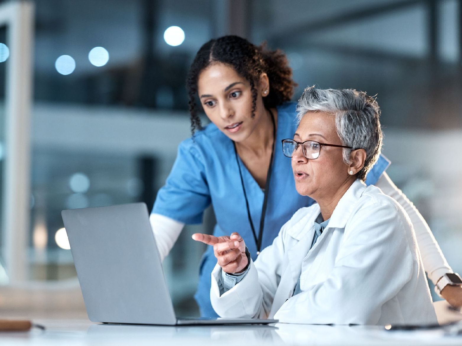 A nurse and a doctor are looking at a laptop computer.