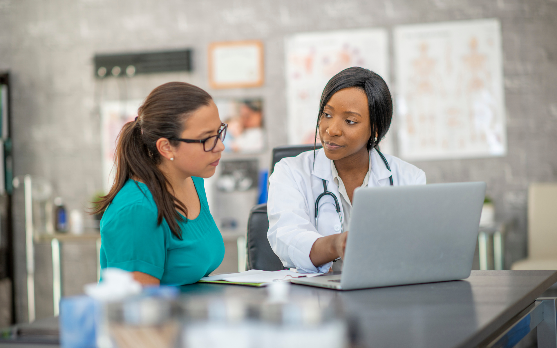 A doctor and patient sitting at table reviewing records on computer