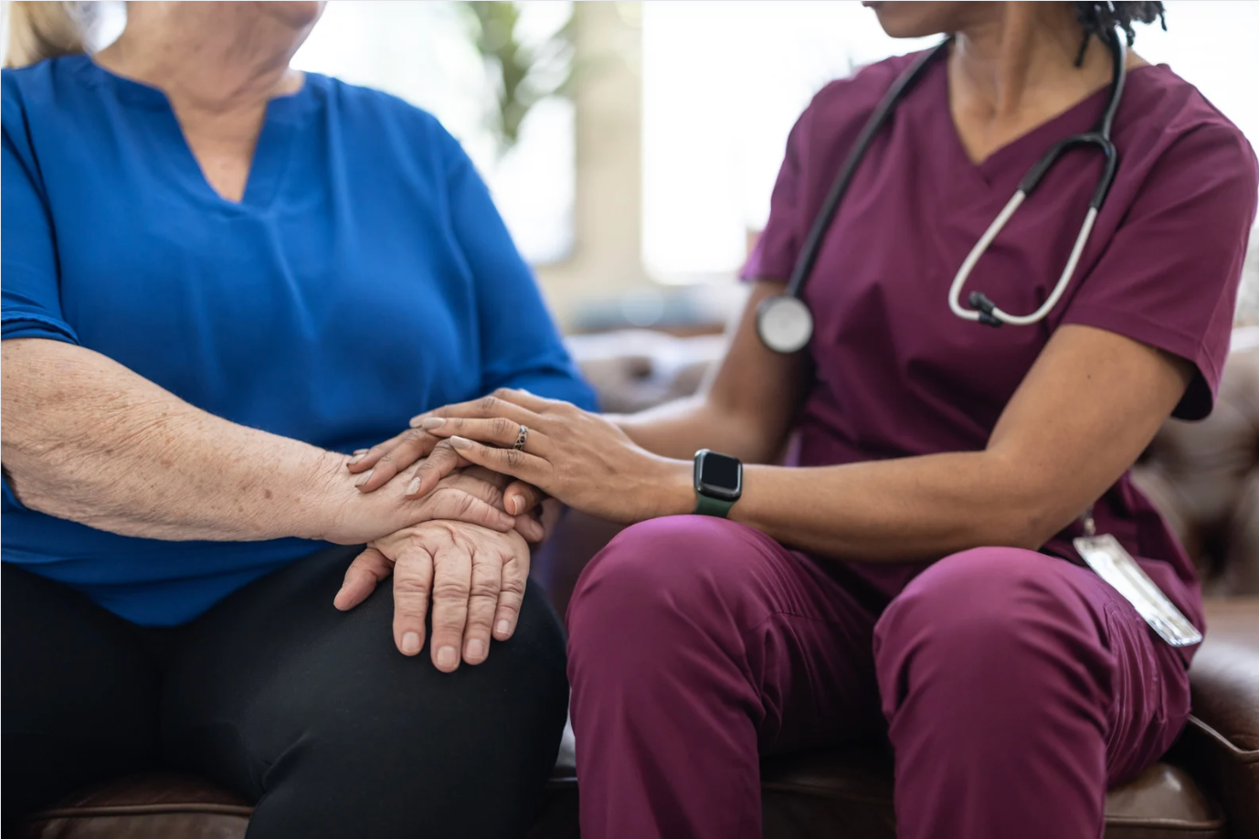 A doctor is holding a magnifying glass in front of a laptop computer.