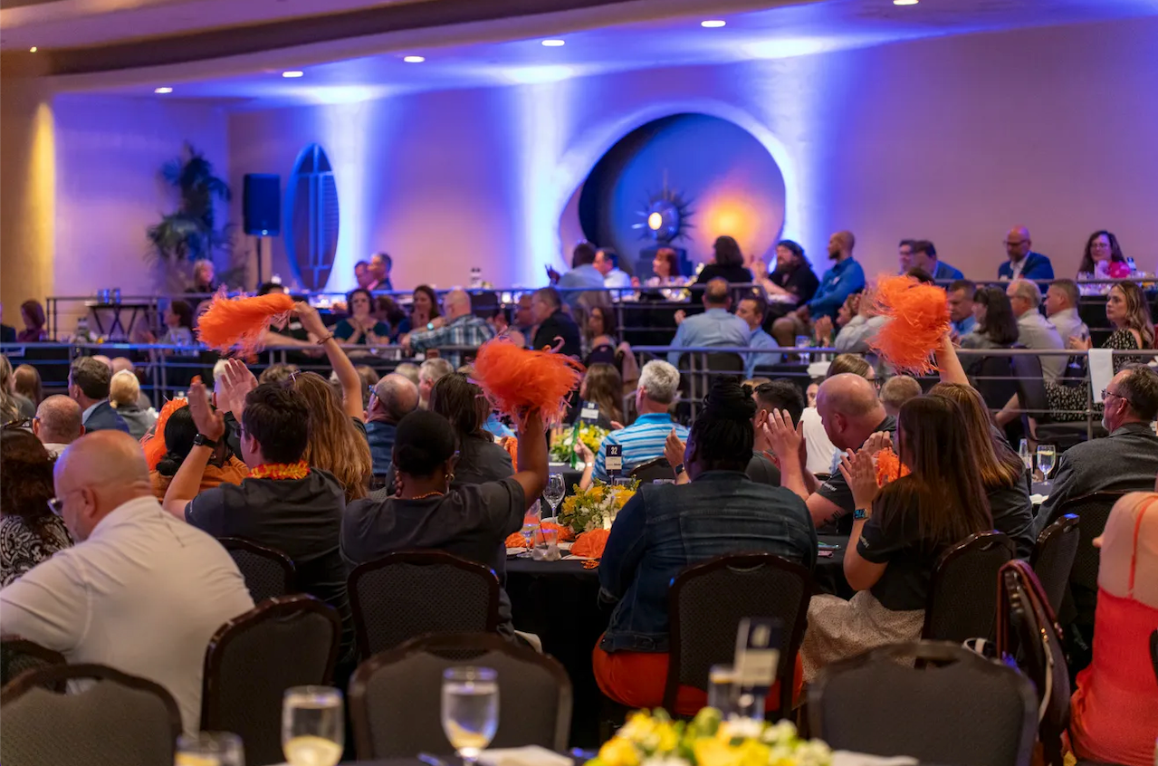 A large group of people are sitting at tables in a large room.